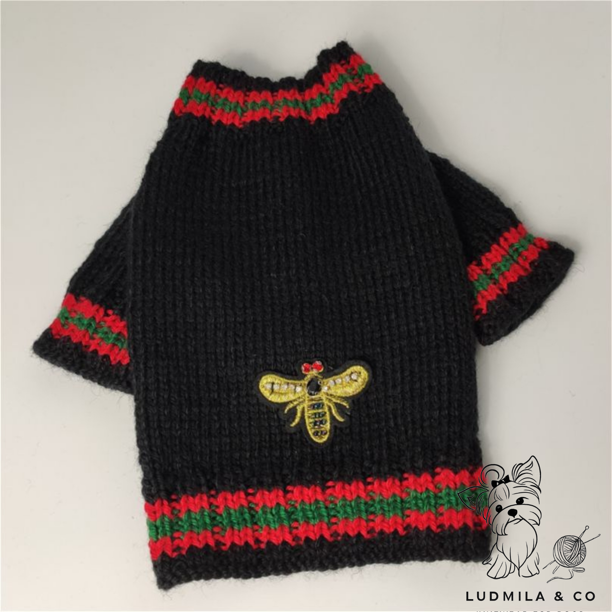 Yorkie wearing black knitted dog sweater with red and green stripes and gold bee embroidery – knitting pattern PDF